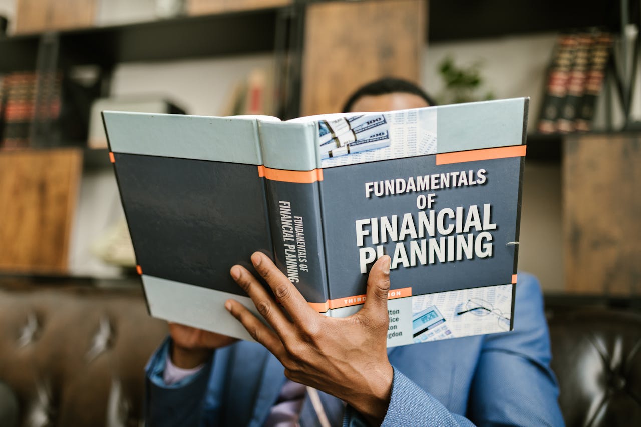about-us A professional individual in a suit reading 'Fundamentals of Financial Planning' indoors.