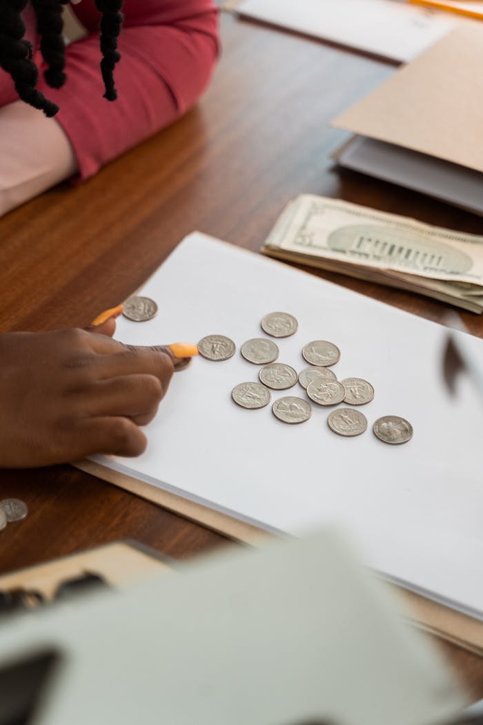 services-05 Close-up of diverse hands counting coins on a wooden table, highlighting teamwork and finance.